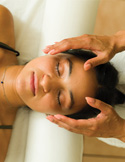 Close-up overhead view of a practitioner placing their hands near a woman's face during a healing session.