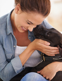 Woman embracing a black dog.