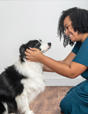 Woman embracing a black and white dog during a healing session.