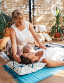 Woman practicing Reiki on a person lying on a mat.