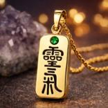 Gold Reiki pendant with engraved Reiki kanji and a small gemstone at the top.